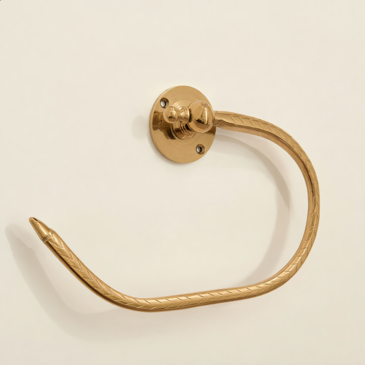 Engraved brass open towel holder mounted on a cream wall