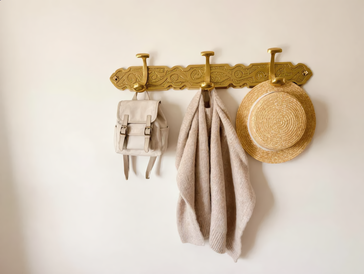 Brass hook rack in a kids room with a backpack, cardigan and hat