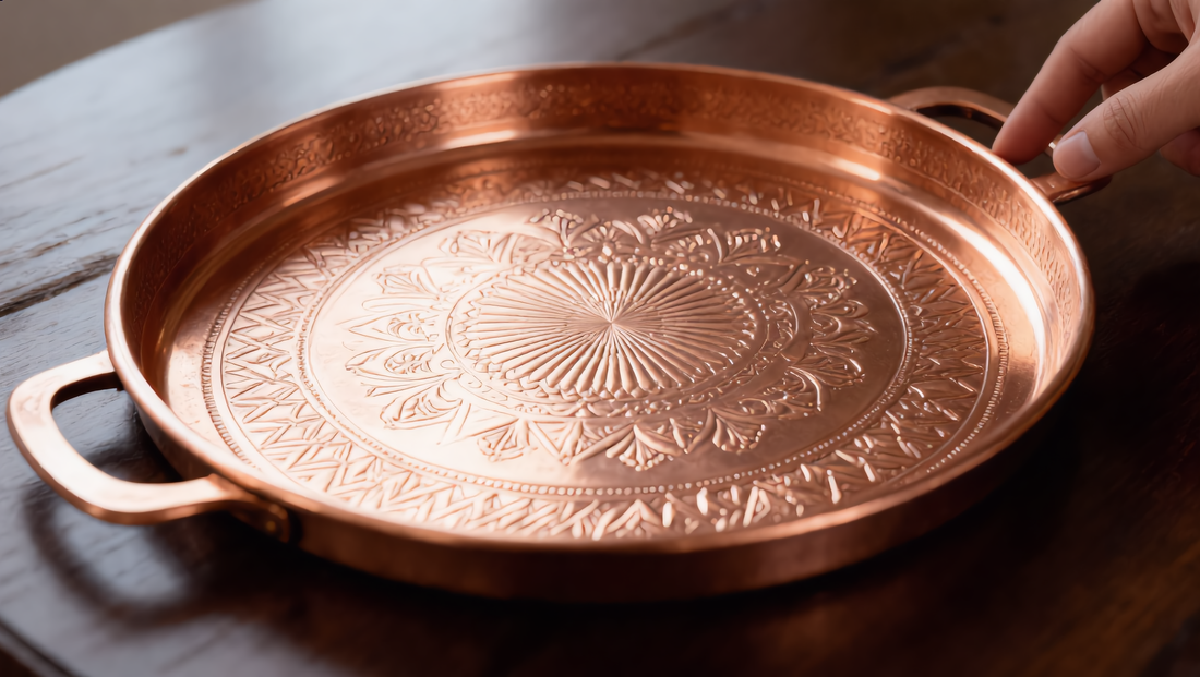 Hand-engraved Moroccan copper tray with a fingertip tracing the pattern