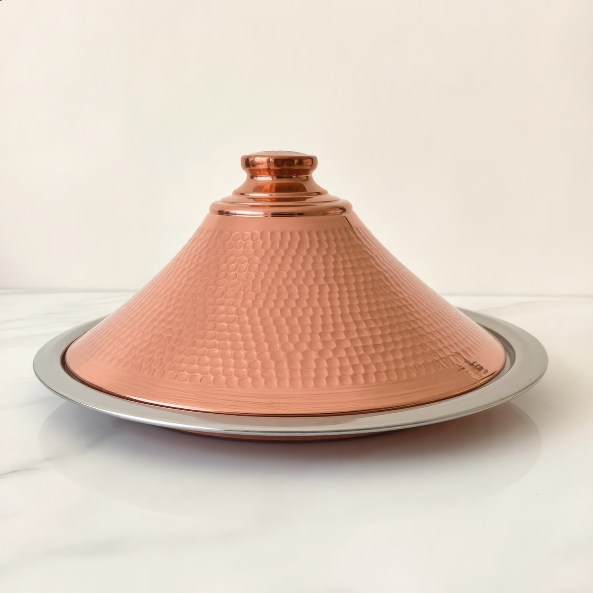 Dyafa hand-hammered red copper tajine on white marble, Cuivra