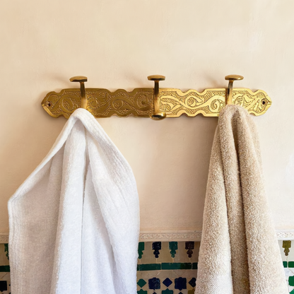 Brass hook rack with a bathrobe and towel in a Moroccan bathroom