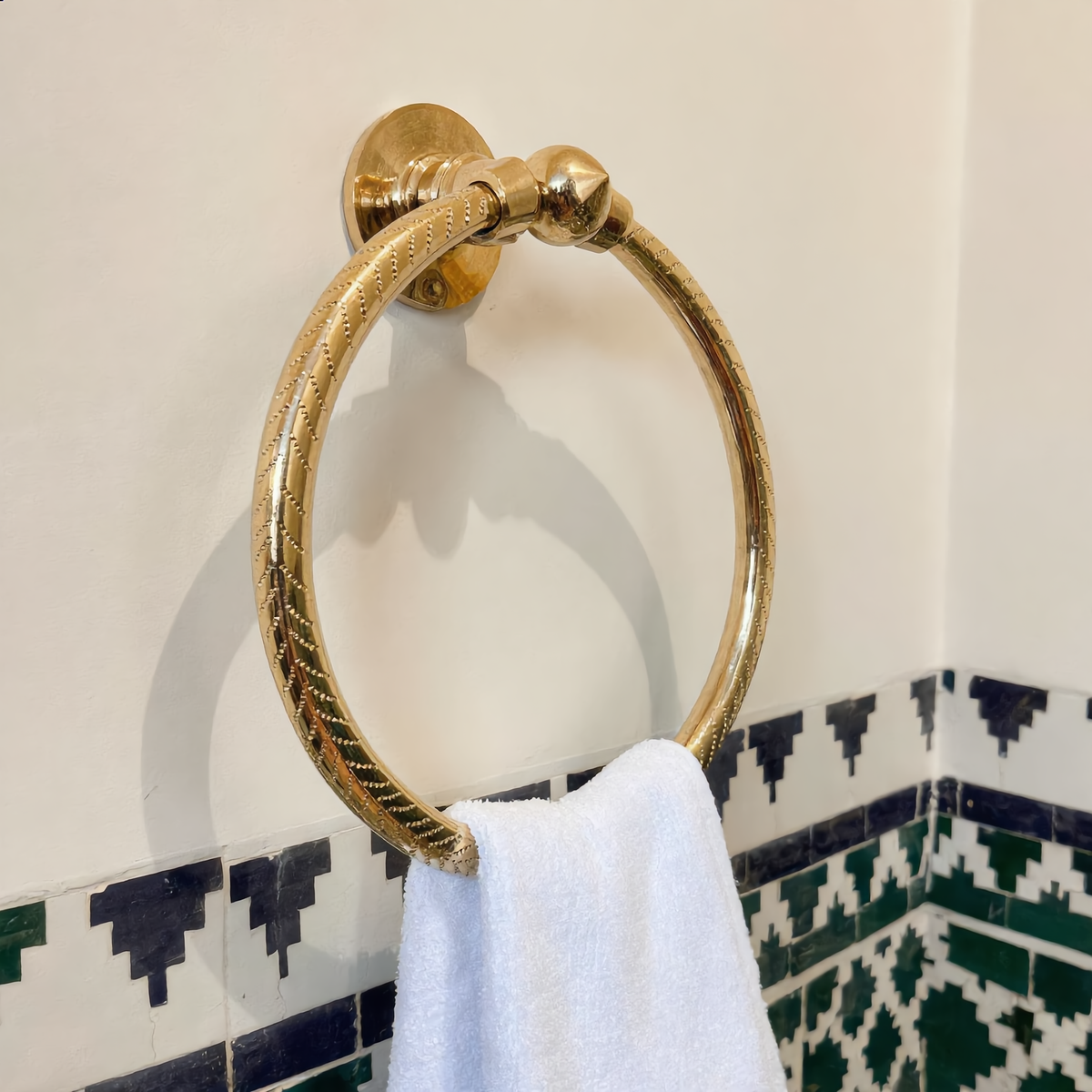 Brass towel ring with a white hand towel in a Moroccan bathroom with zellige