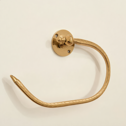 Engraved brass open towel holder mounted on a cream wall
