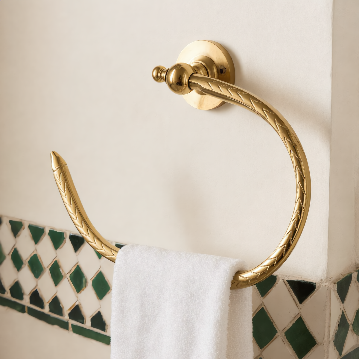 Open brass towel holder with a white hand towel in a Moroccan bathroom, Cuivra