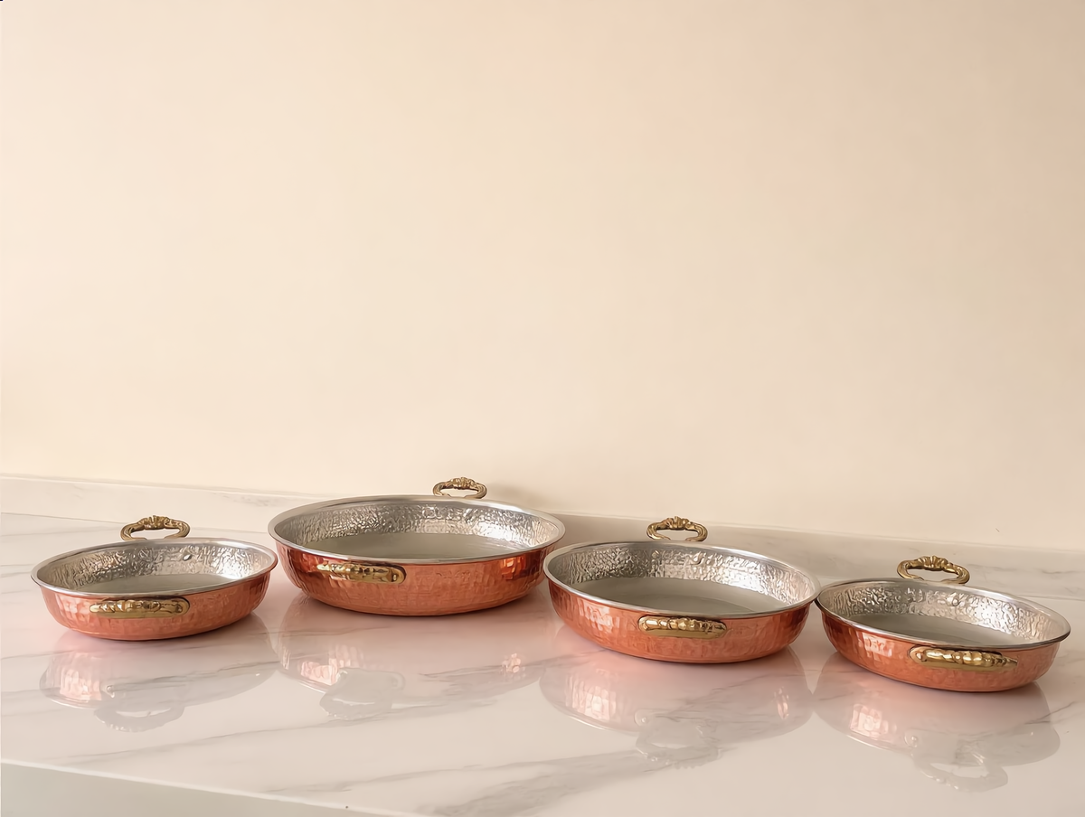 Mqila copper pans in four sizes on a marble counter, Cuivra
