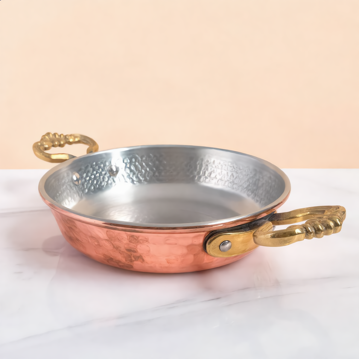 Mqila hand-hammered copper pan with brass handles on white marble, Cuivra