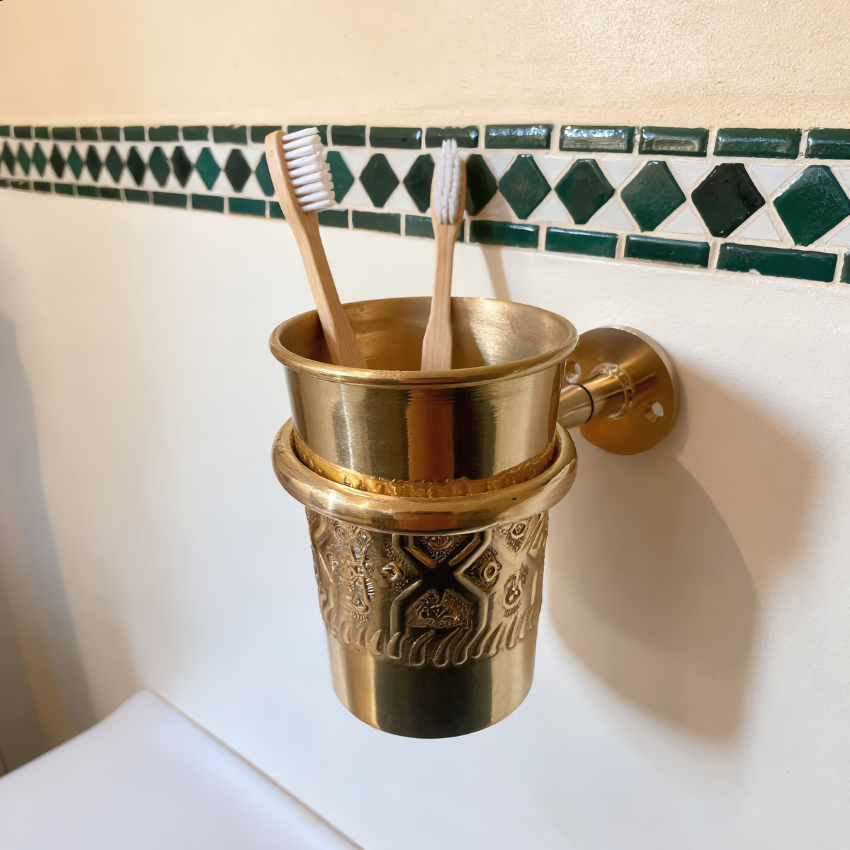 Engraved brass toothbrush cup holder with bamboo toothbrushes in a Moroccan bathroom, Cuivra